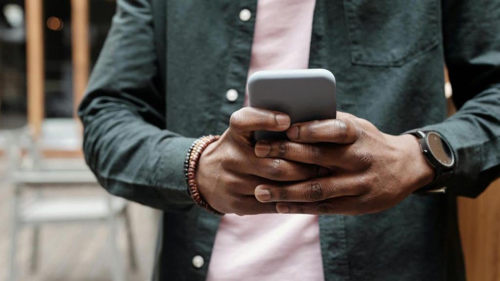 A person holding and using a smartphone outdoors.