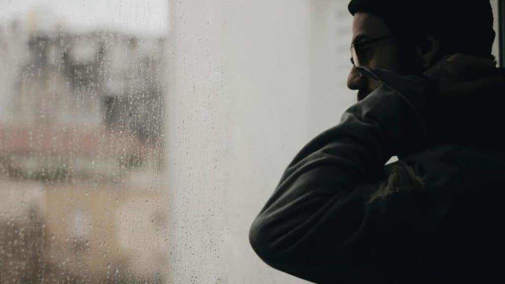 A man looking out a rainy window.