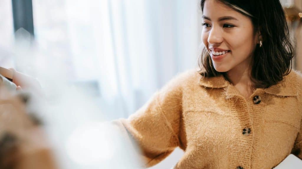 A woman smiling while looking at someone nearby.