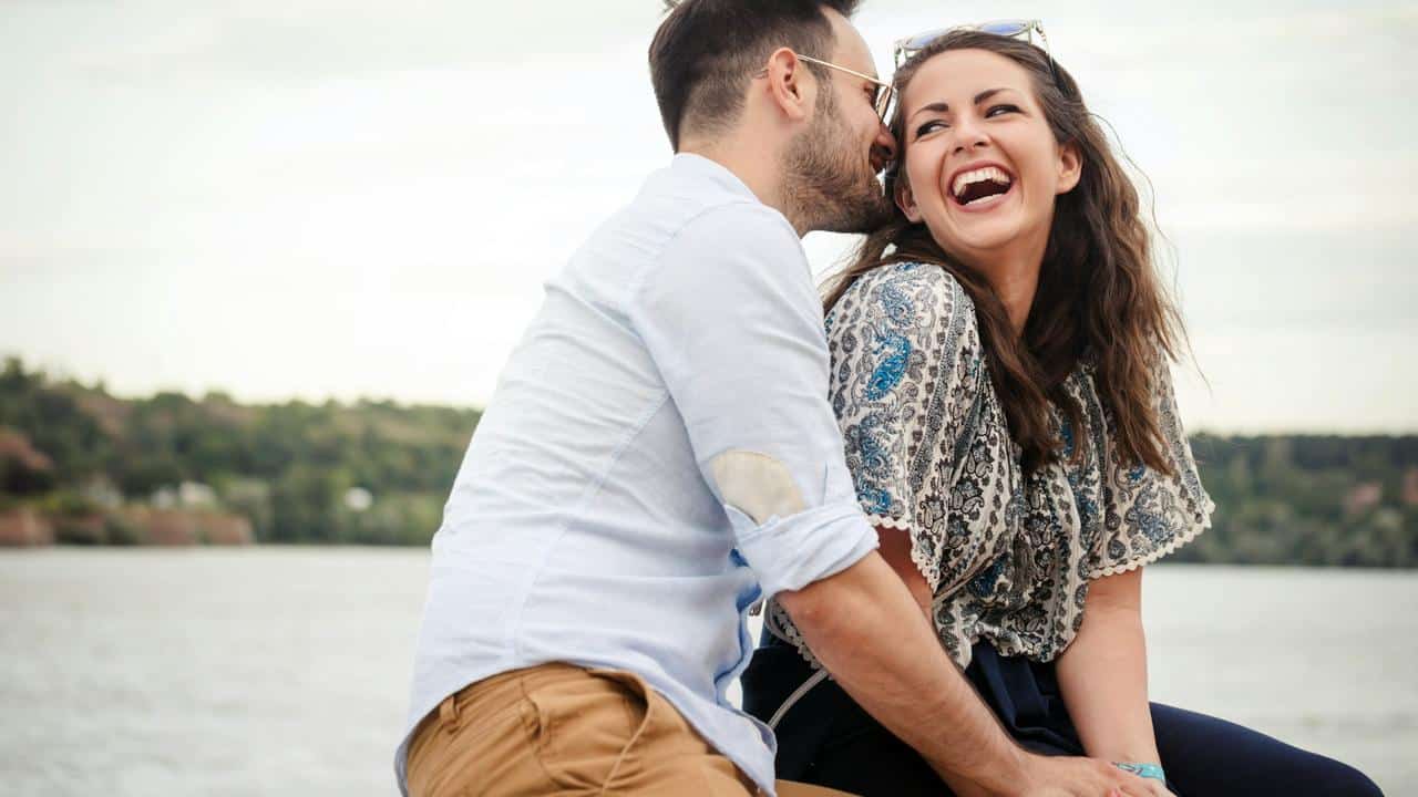 A man whispering to a laughing woman