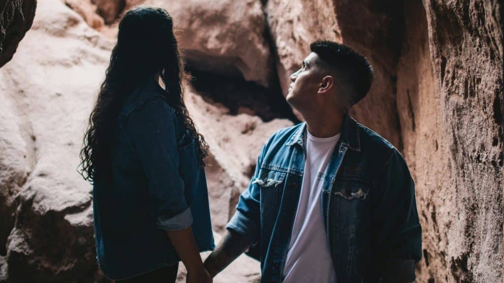 Couple in denim jackets holding hands in a rocky canyon.