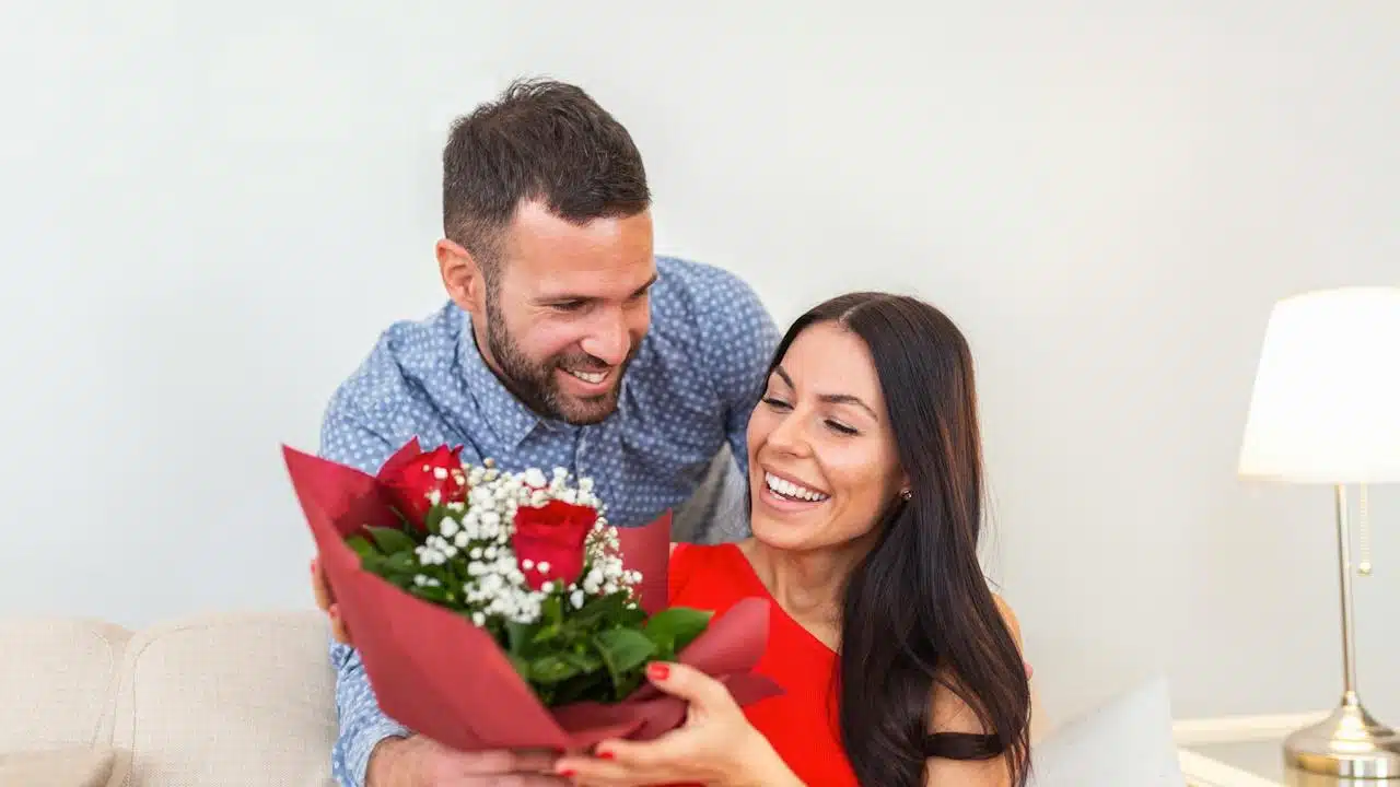 A man giving his wife a bouquet of flowers in order to appreciate her.