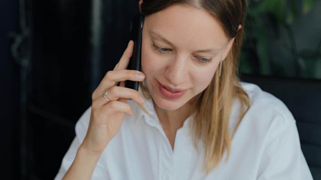 A woman in a white shirt talking on a phone