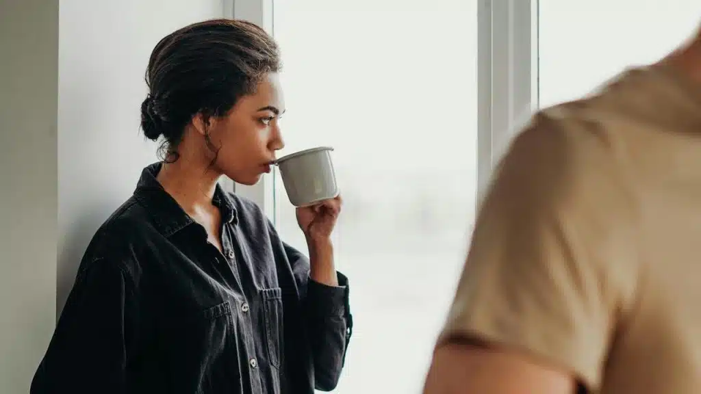 A woman in a dark shirt drinking from a mug