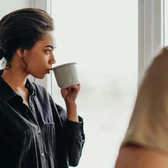 A woman in a dark shirt drinking from a mug