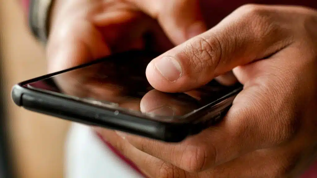 A close-up of hands holding and using a smartphone.