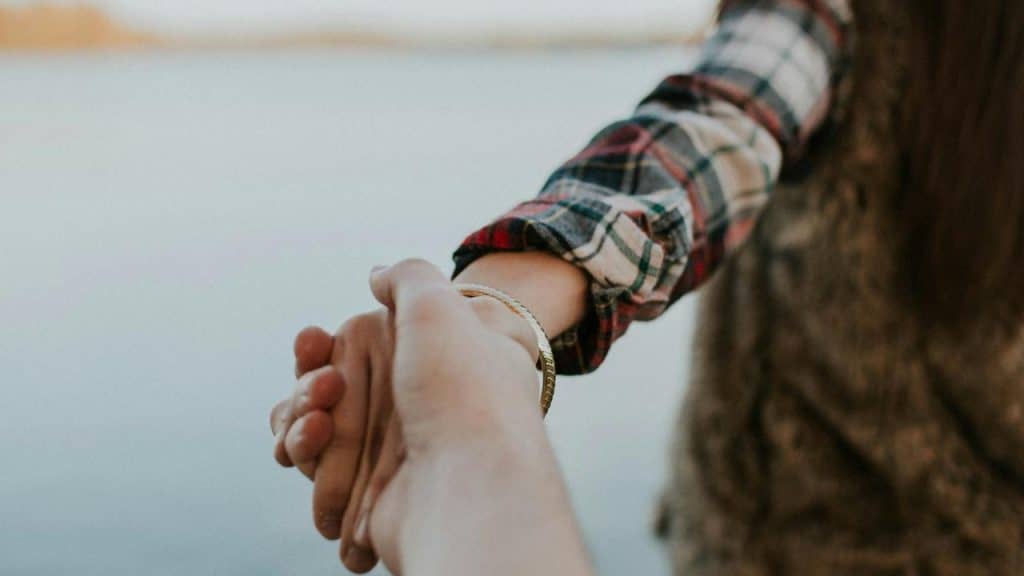 A person in a plaid shirt holding another person’s hand.