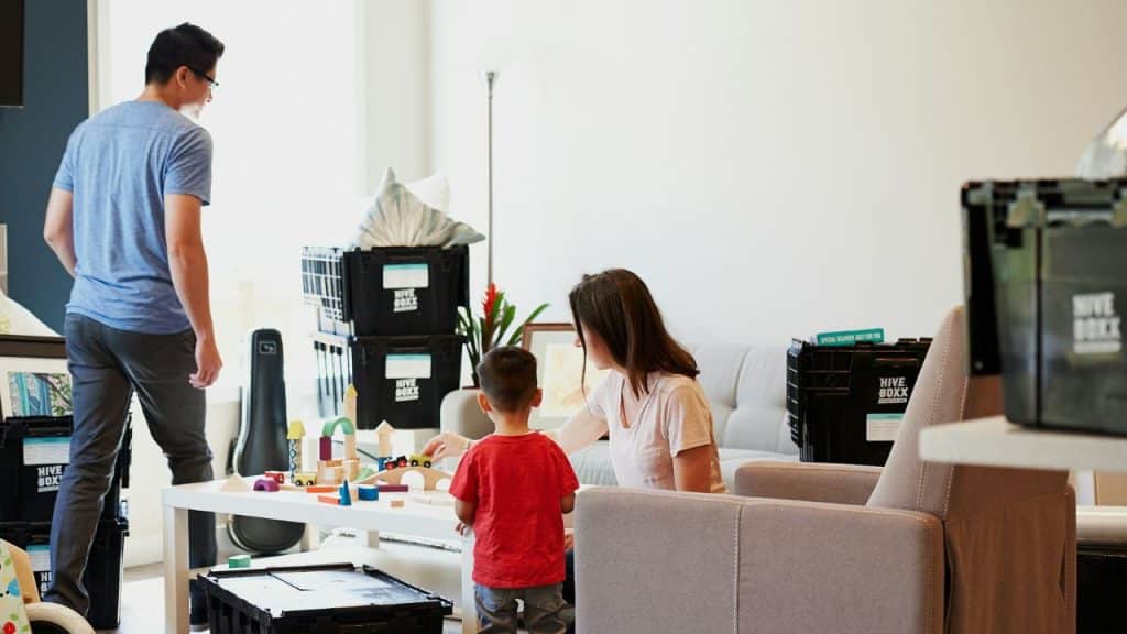A woman and child play with blocks on a table while a man walks away.