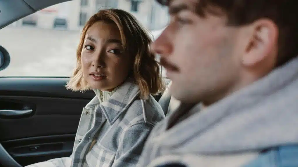A woman looking at a man while sitting together in a car
