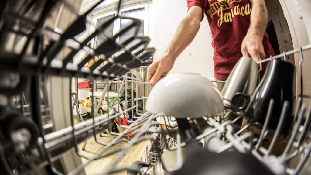 A person loading dishes into a dishwasher.