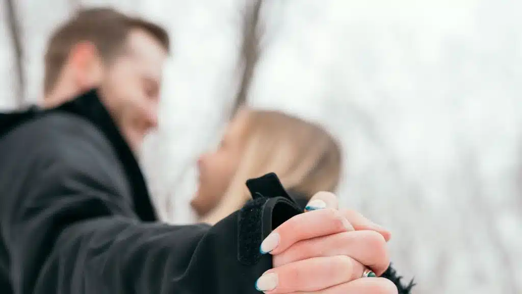 A man and a woman holding hands in the snow.