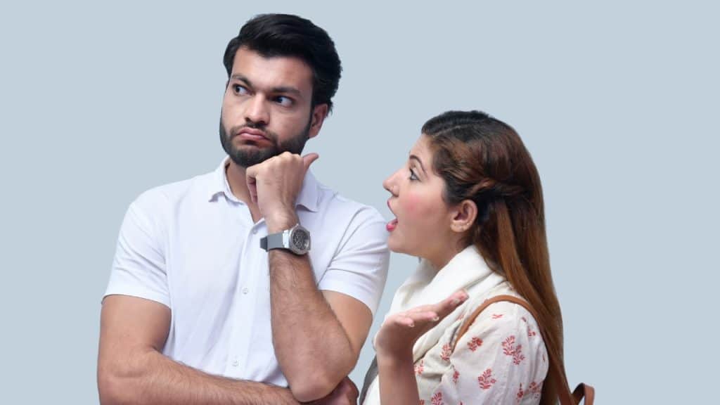 A man looks away with his hand on his chin while a woman speaks.