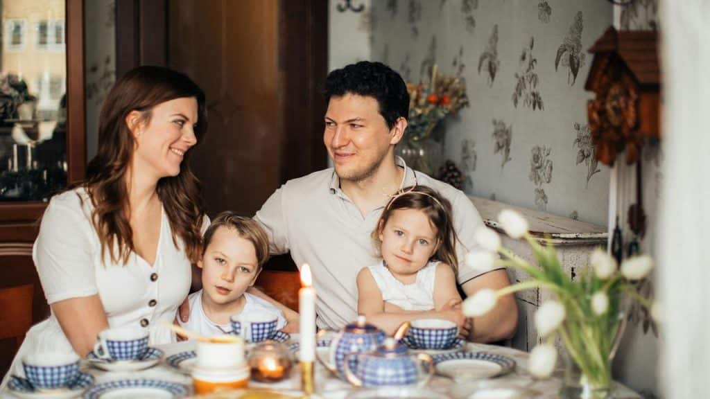 A family of four sitting together at a dining table with tea and candles.