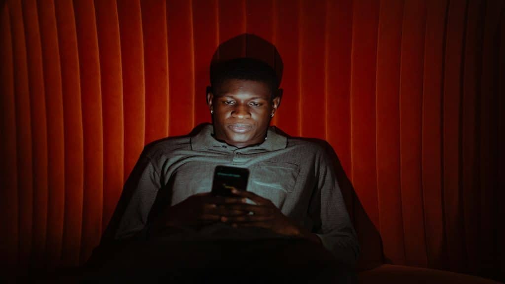 man looking at phone privately in dark room