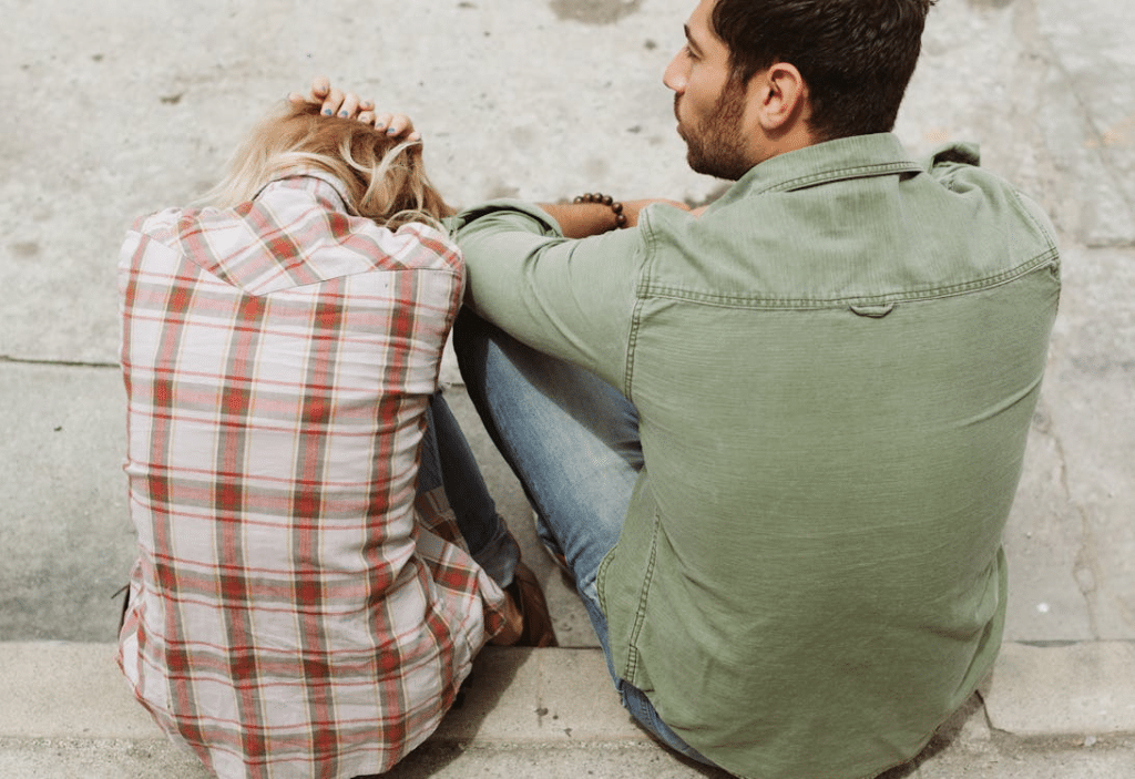 Unhappy couple sitting and woman cowering in fear