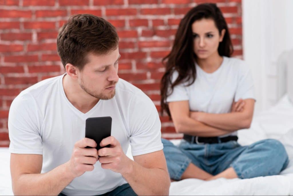 Woman looking at the man that uses phone