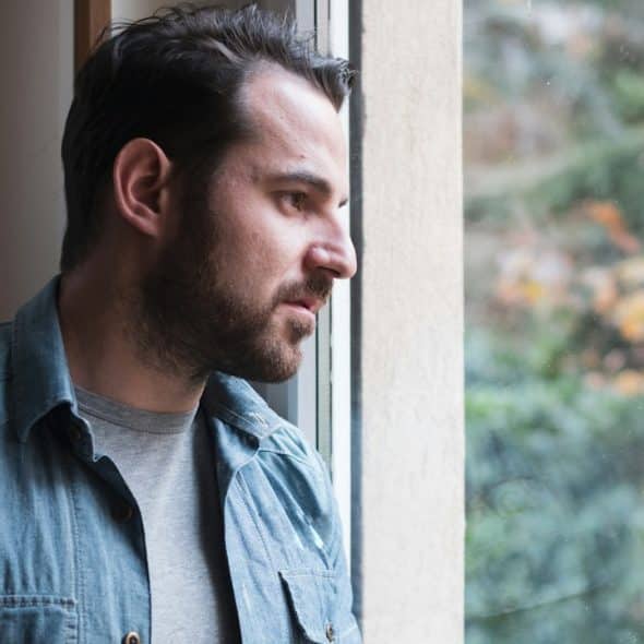 Thoughtful man looking out of window.