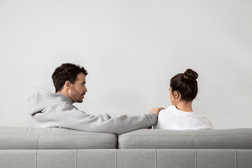 Woman ignoring man trying to catch her attention in living room