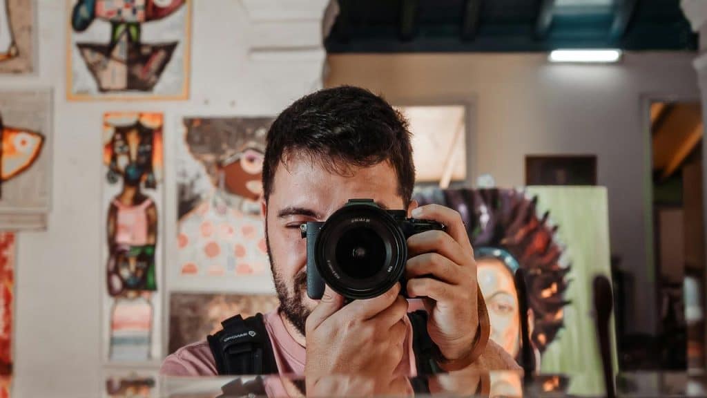 A man taking a photo with a camera indoors.