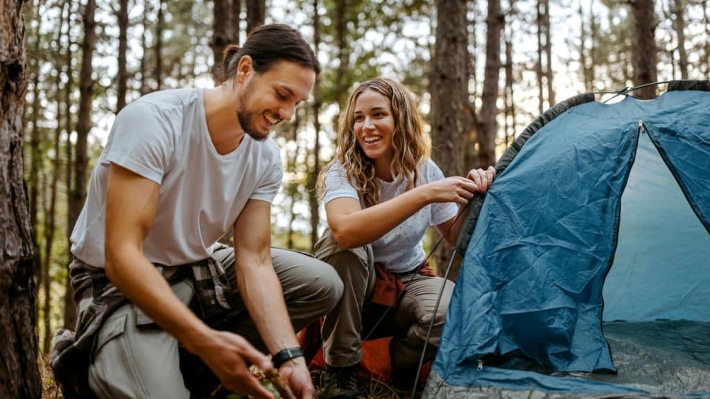 An outdoor couple setting up a blue tent