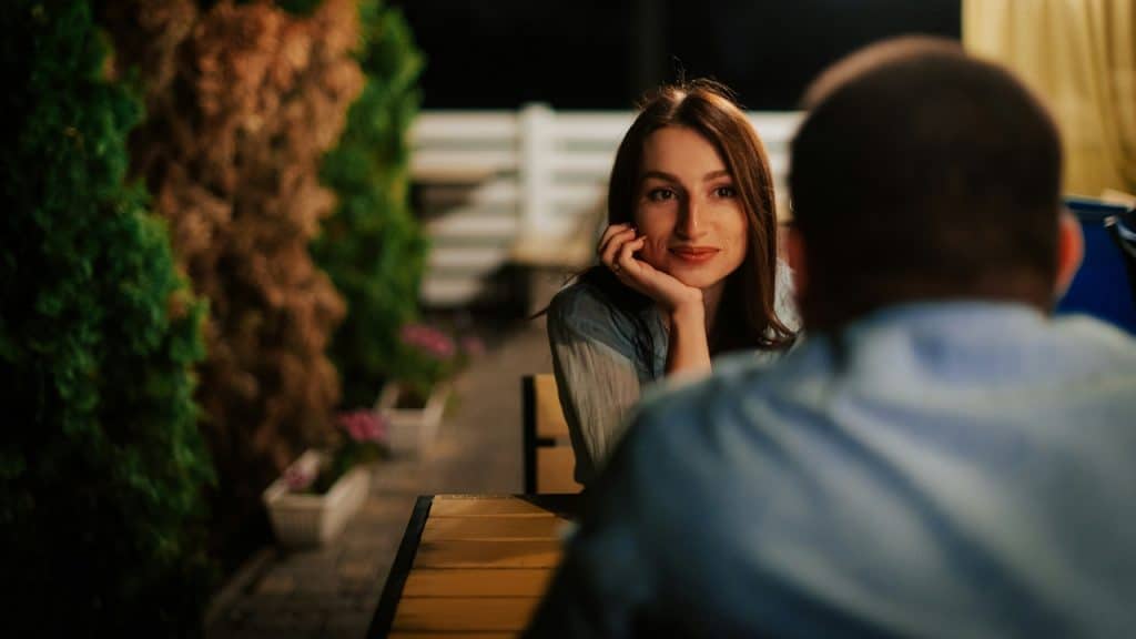 A woman rests her chin on her hand while looking at someone off-camera.