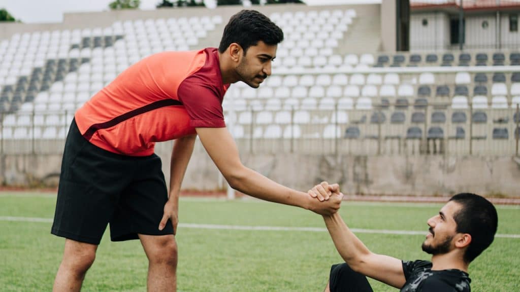 A man is helping another man with a soccer ball.