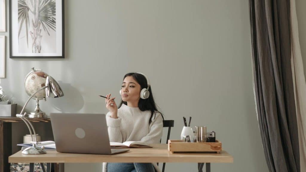 A woman wearing headphones sitting at a desk with a laptop.