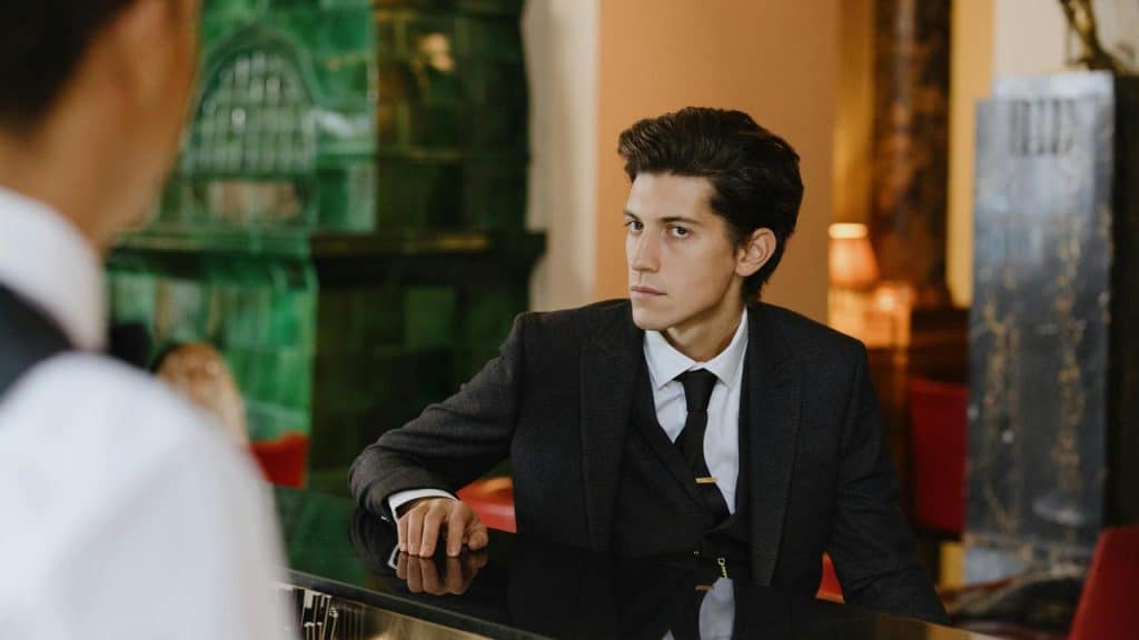 A man in a suit leaning on a bar counter