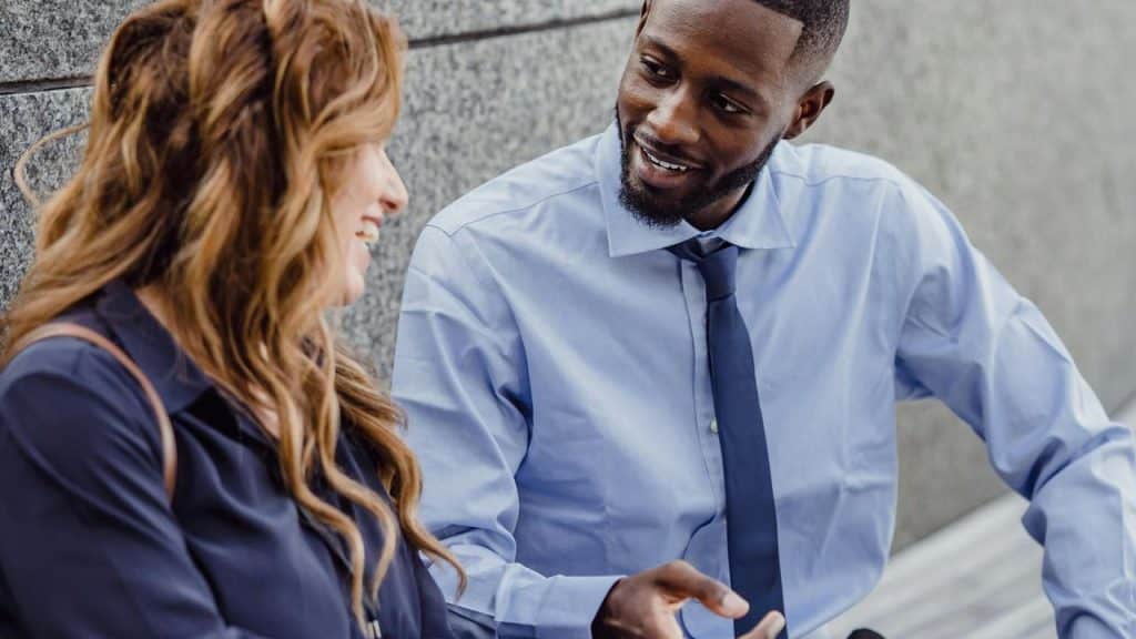 A man and woman smiling and talking outdoors.