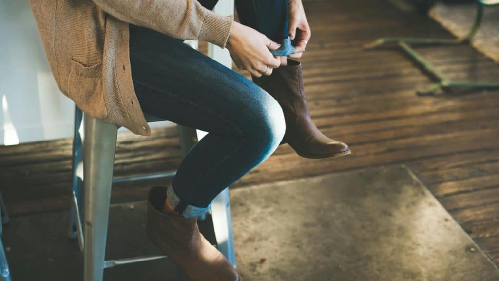 A person sitting and adjusting their boot.