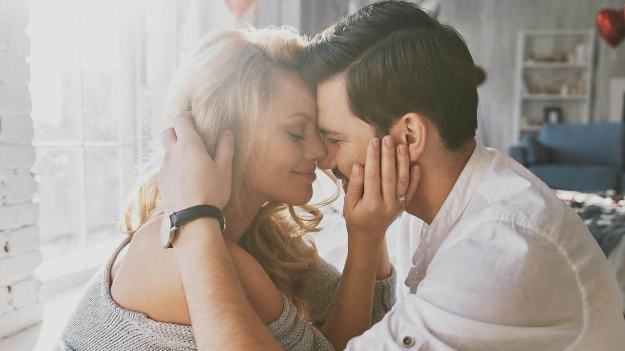 Young couple embracing and smiling in the bedroom.