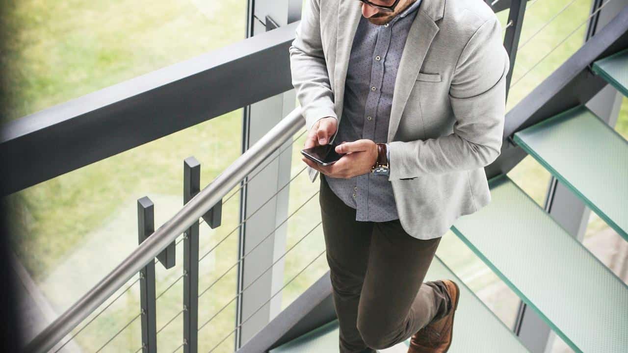 A man in a blazer checks his phone