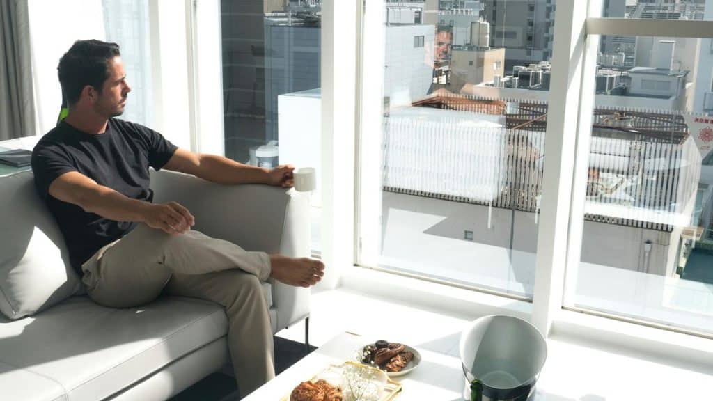 A man sitting on a couch and looking out a large window.