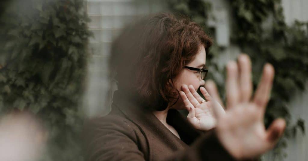 A woman turning away and raising her hand as if to block the view.