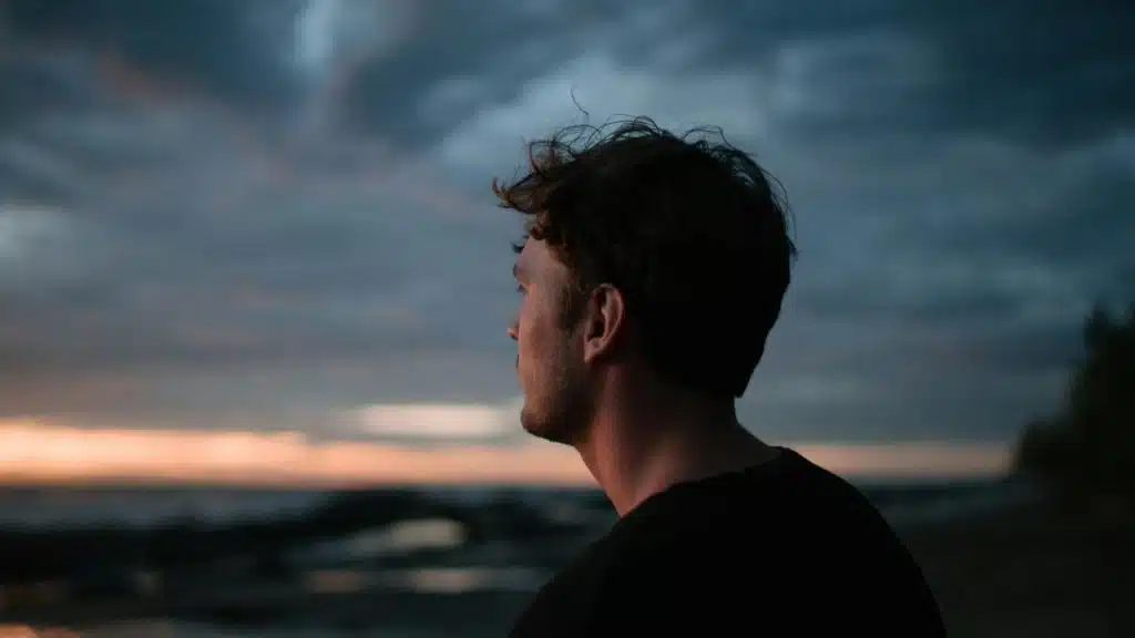 A man looking out at the horizon during sunset.