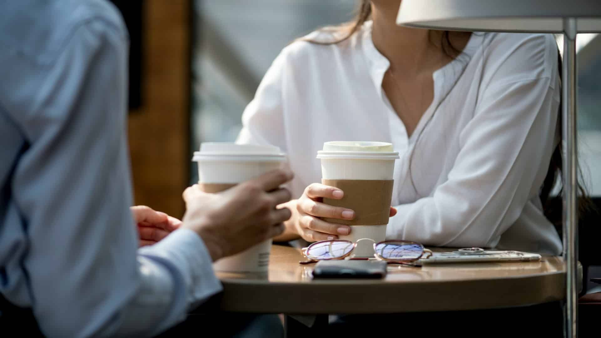 woman handing coffee to partner