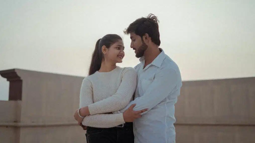 A couple hugging each other while standing on the rooftop of their home.