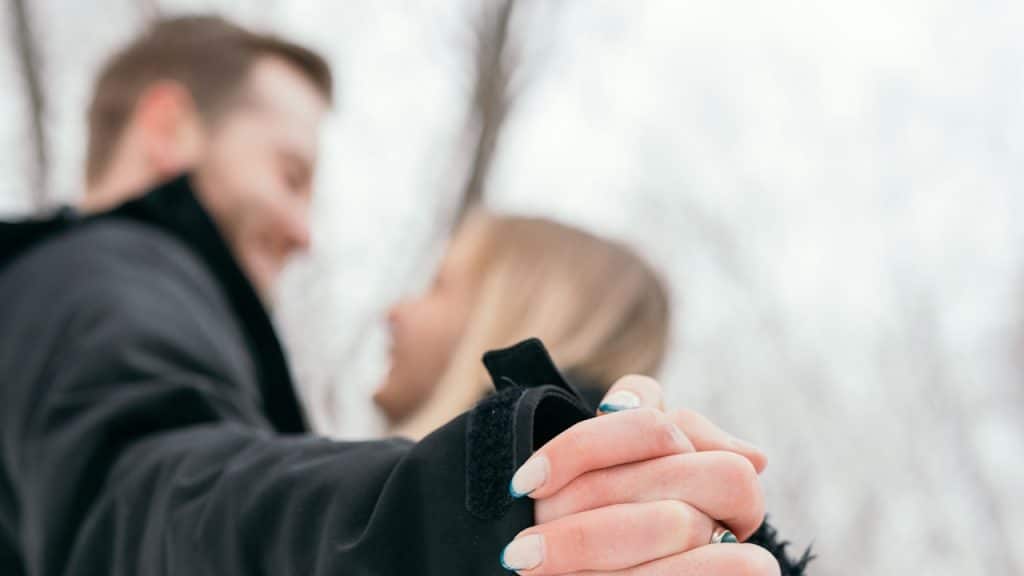 A man and a woman holding hands in the snow.