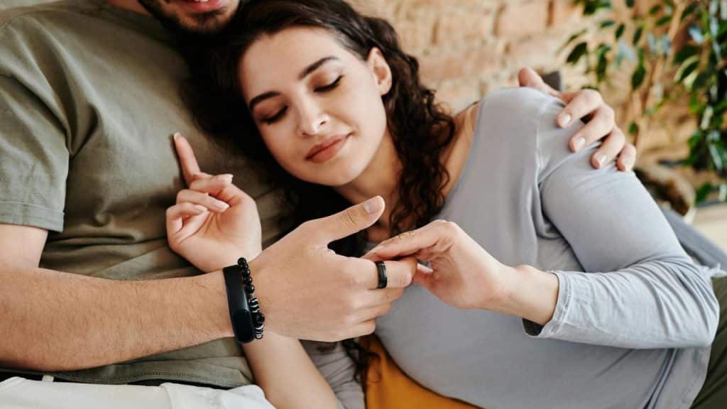 A woman rests against a man while holding his hand 