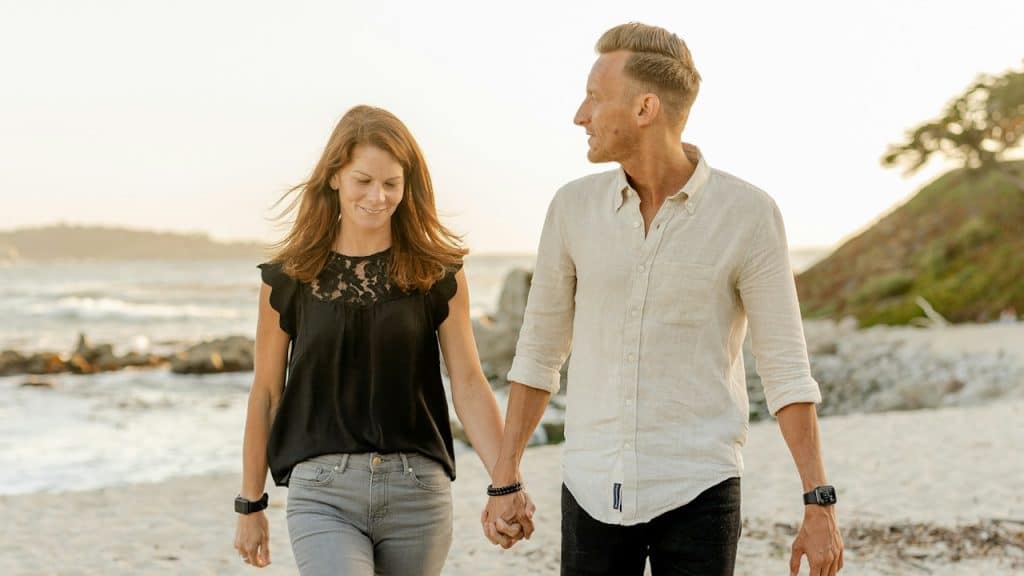 A man and woman are standing on the beach during the daytime.