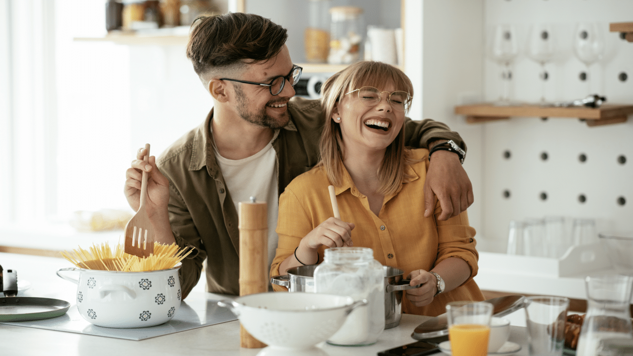 A couple laughing together in the kitchen