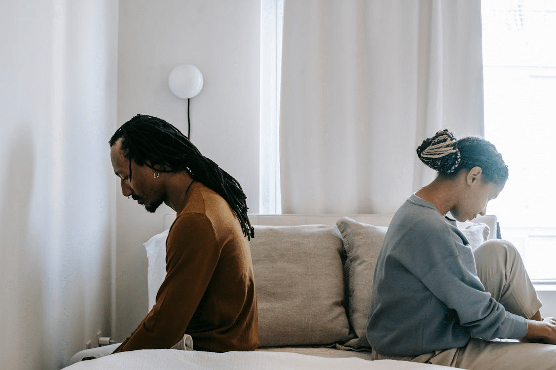 A couple in bed, sitting apart in misunderstanding