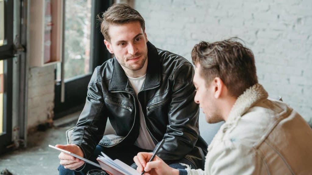 A two men sitting together reviewing documents indoors.