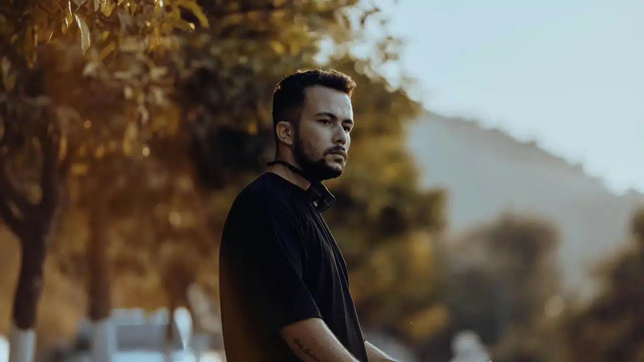 A man standing outdoors near trees, looking off into the distance