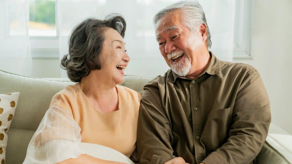 A couple is smiling while sitting on a sofa in the living room.