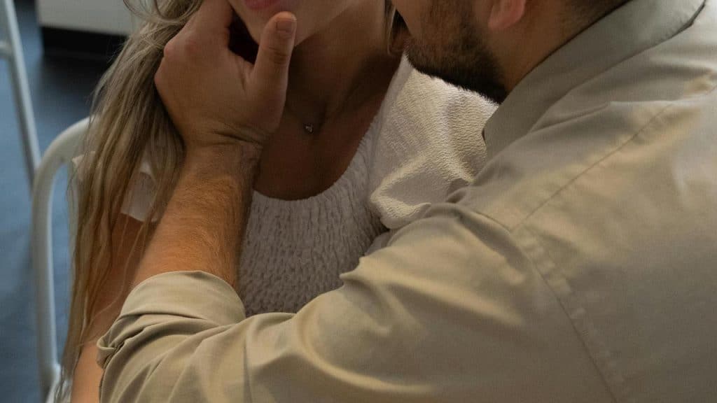 A man gently touching a woman’s face while sitting close together.