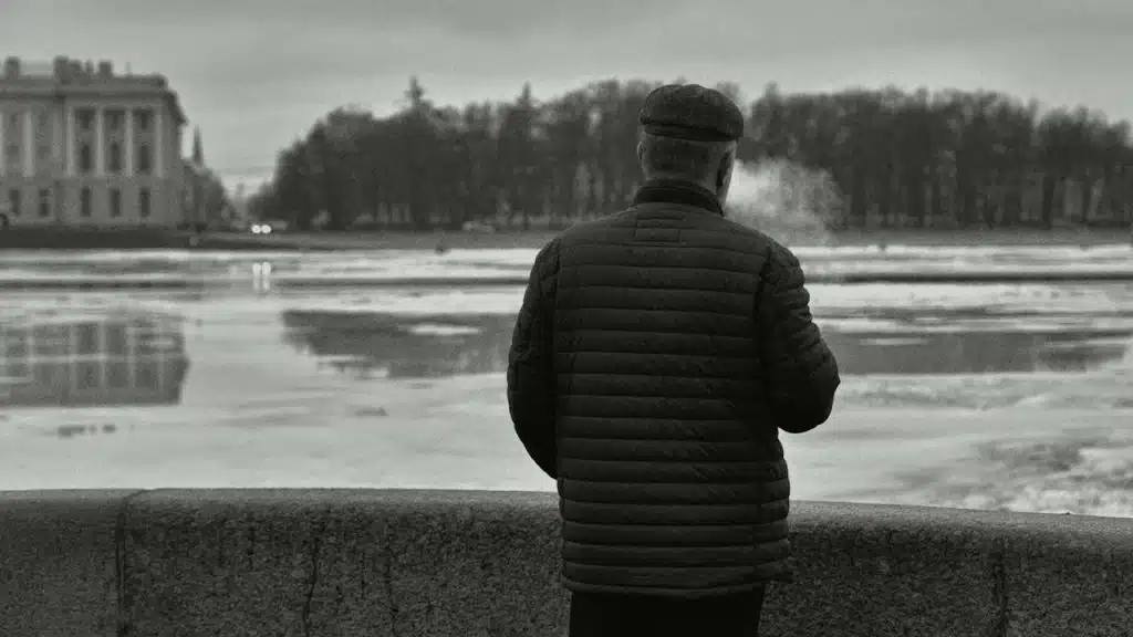 A man standing on wall looking at a body of water.