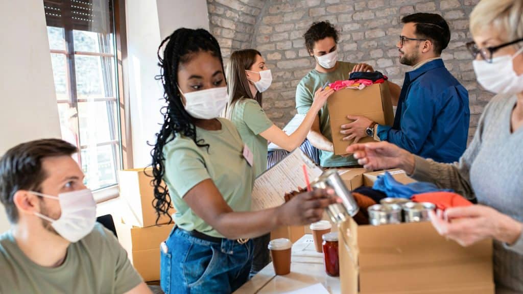 A group of people wearing face masks at a food charity drive.