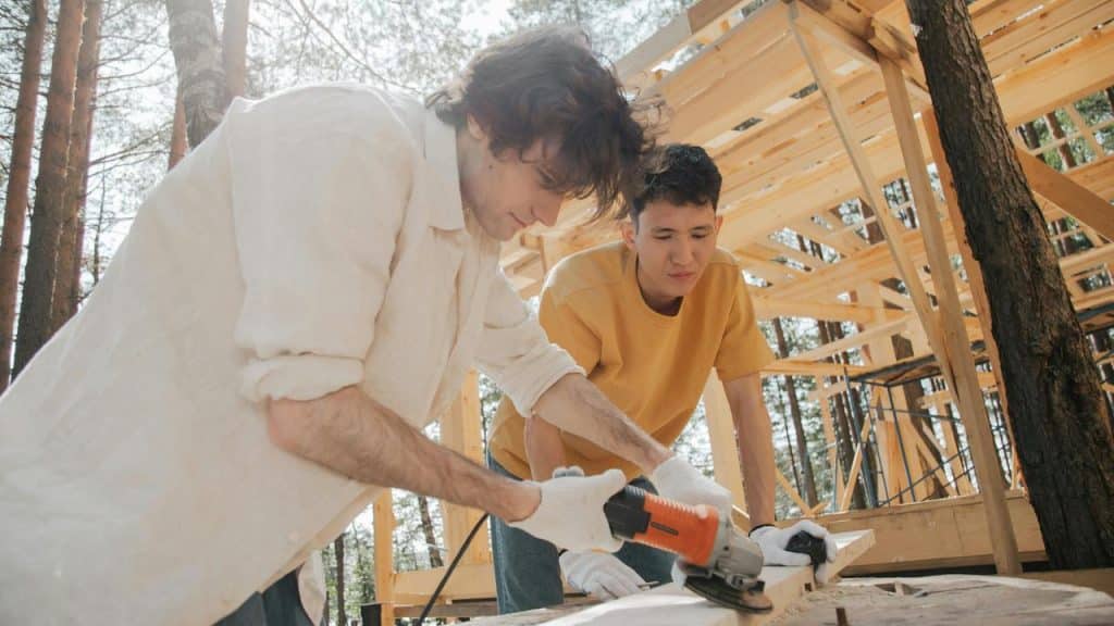 A man using a power tool while another man watches.
