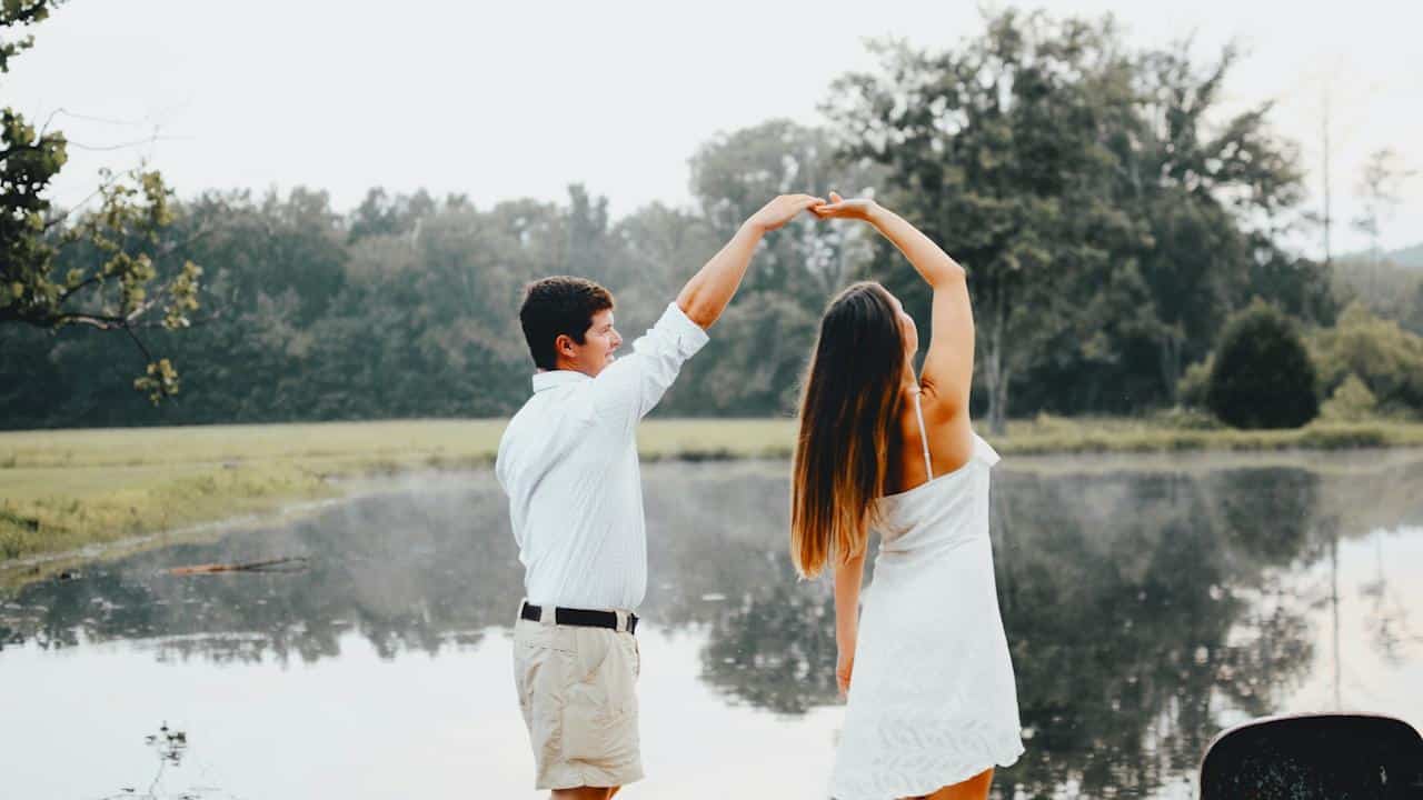 A man and woman dancing near a body of water.
